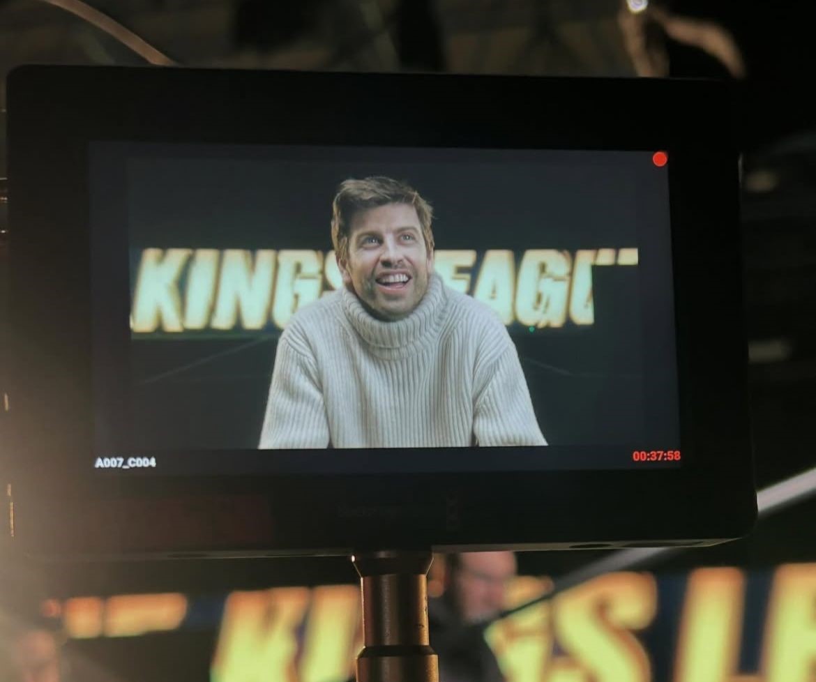 Gerard Piqué con jersey de cuello alto frente a un fondo con letras luminosas que dicen ‘KING’S LEAGUE’, grabado en estudio profesional.