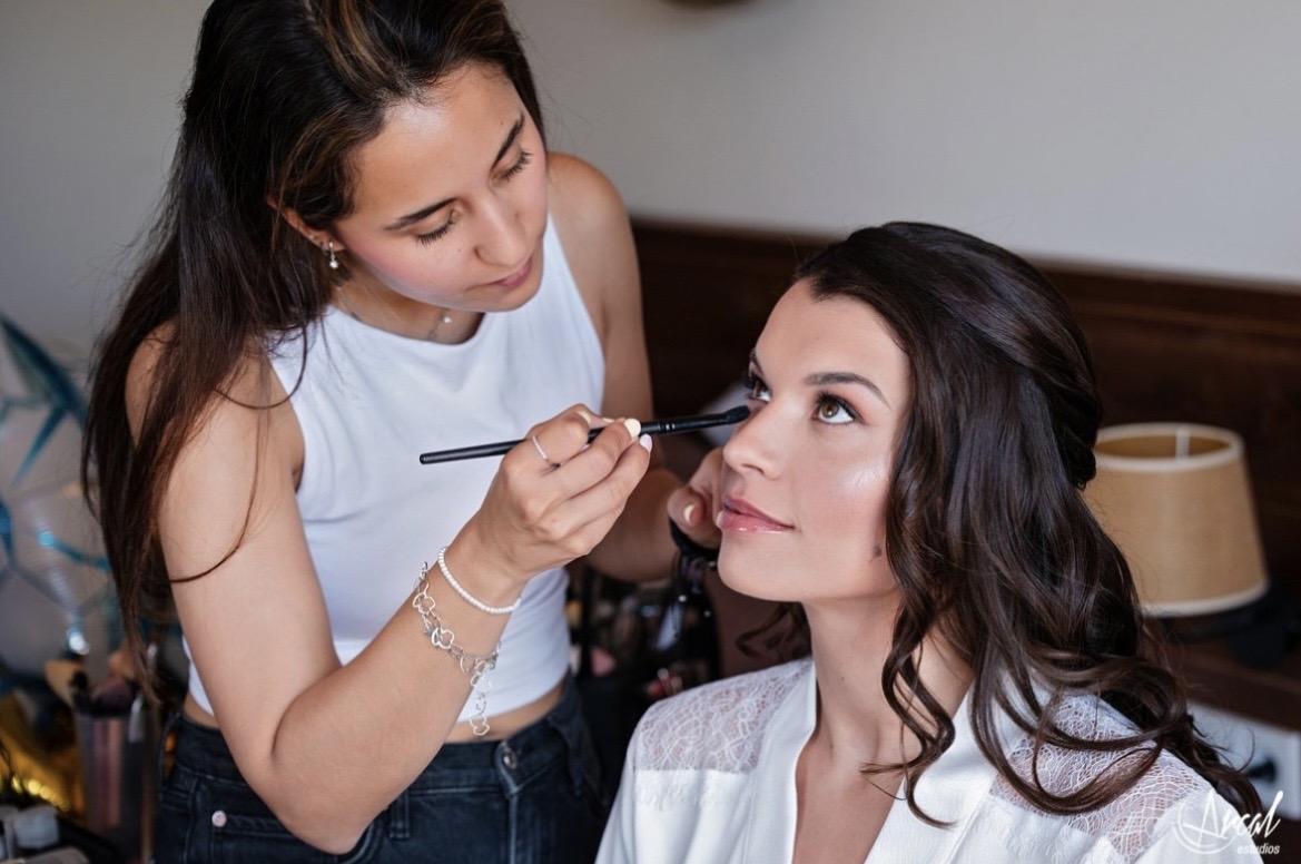 Maquilladora aplicando maquillaje a una mujer durante una sesión de belleza